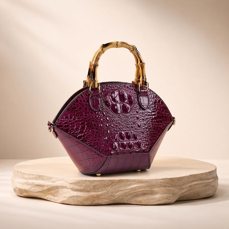 Sac coquille effet croco violet à anse bambou, posé sur un socle en pierre, vue produit