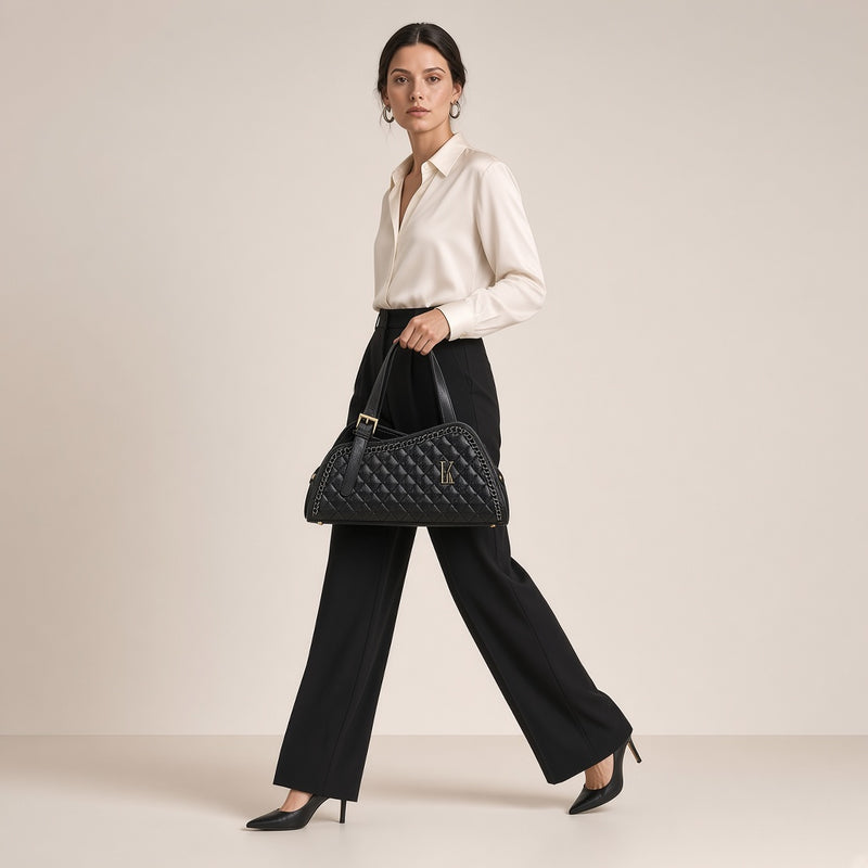Sac porté épaule en cuir matelassé noir à chaîne, tenu à la main en marchant