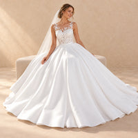 Robe de mariée longue blanche en dentelle, pose assise montrant la jupe ample