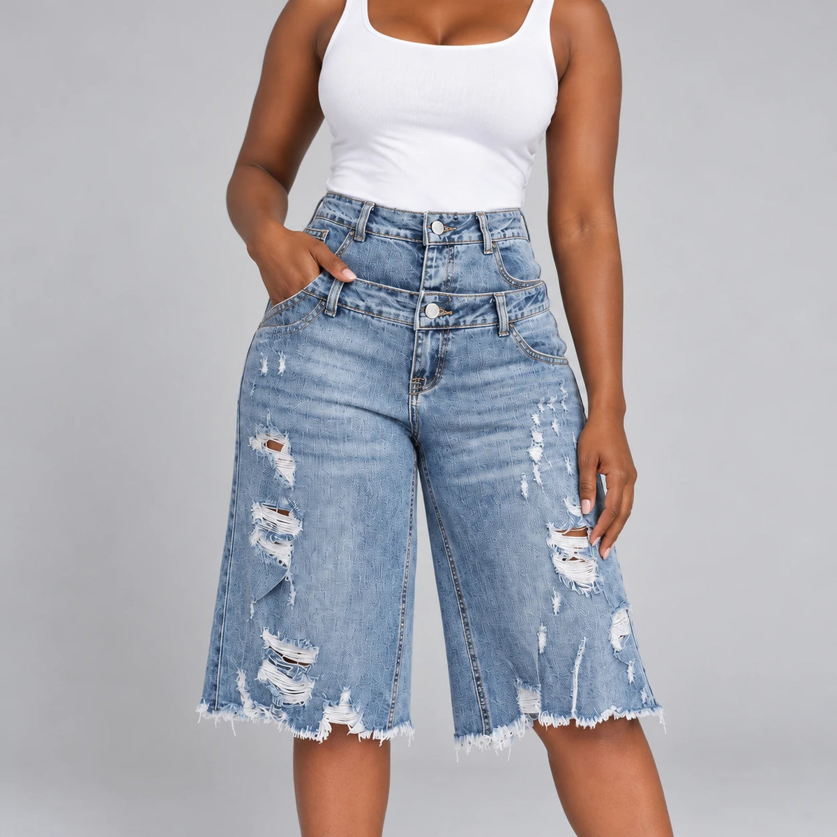 Détail de la double ceinture boutonnée et du denim déchiré du bermuda bleu