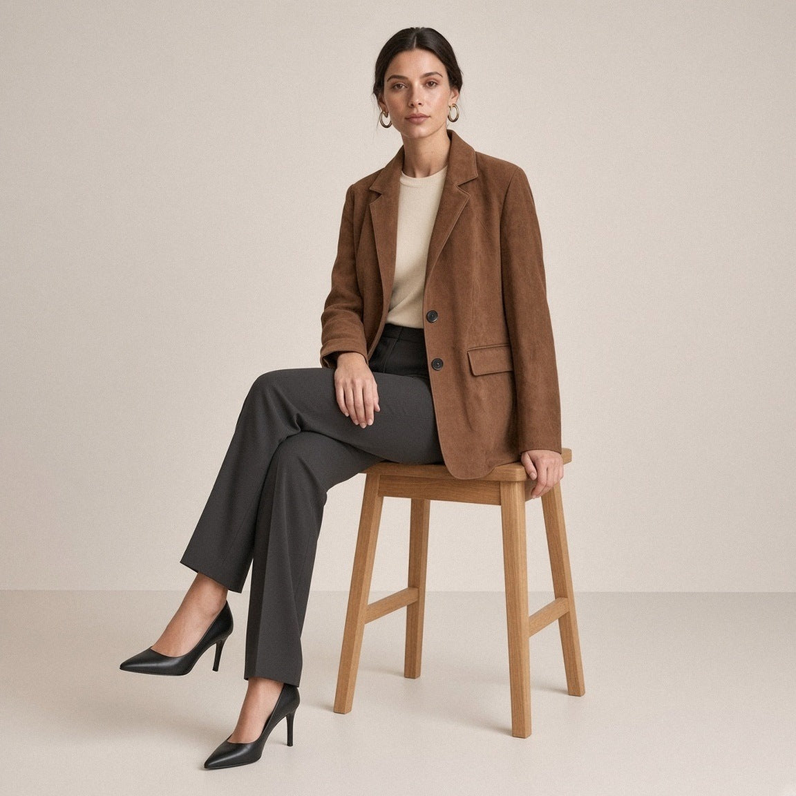 Blazer mi-long en daim de mouton brun tabac SAKIWE porté assise sur un tabouret