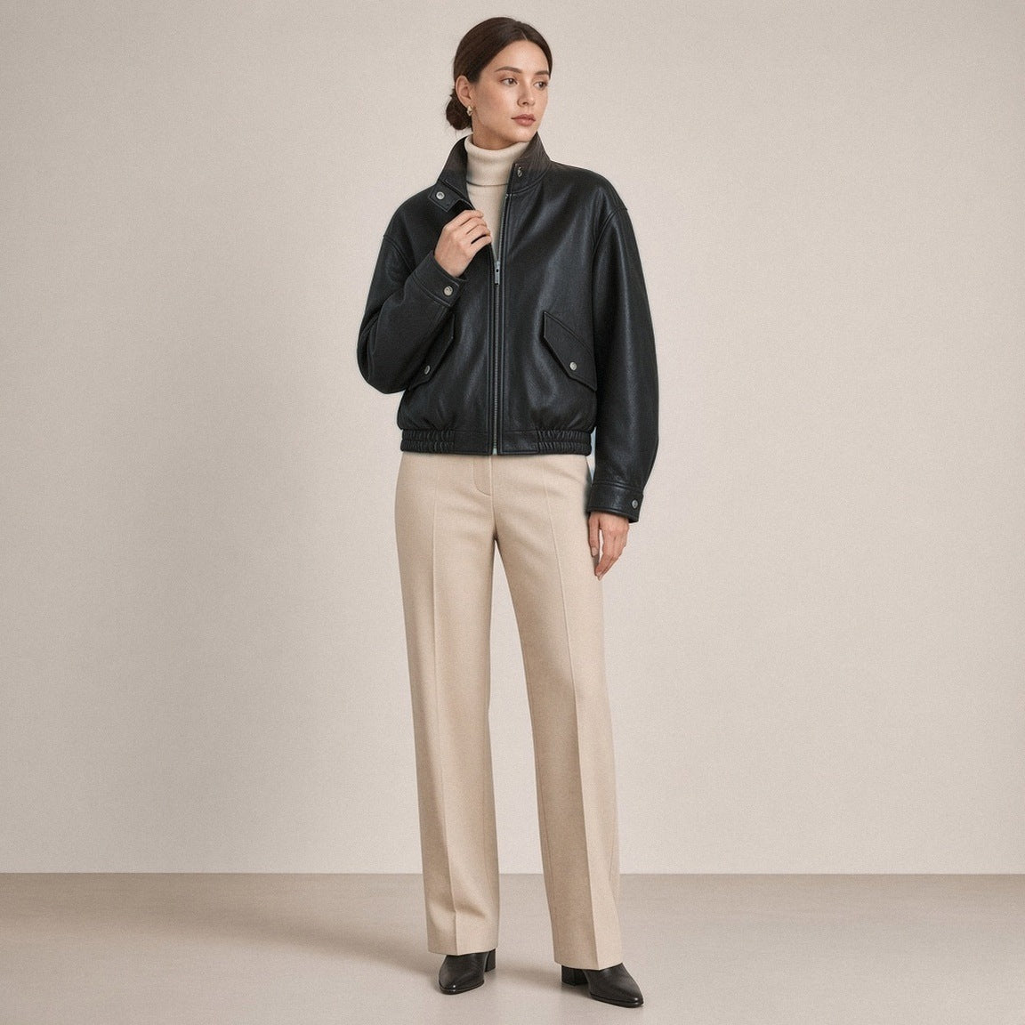 Blouson court en cuir de mouton à col montant noir porté, main au col