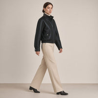 Blouson court en cuir de mouton à col montant noir porté, vue de profil en marche
