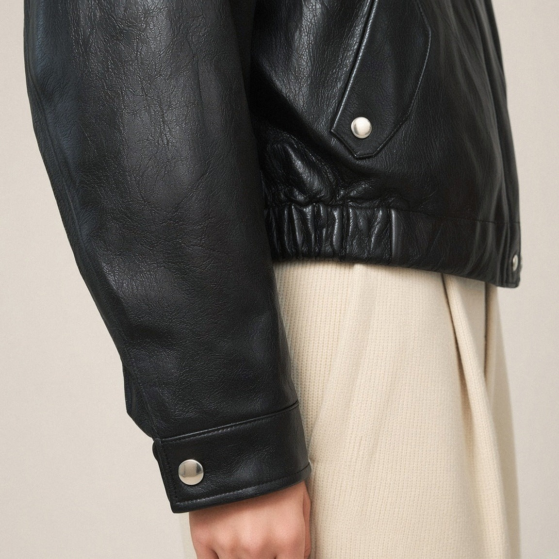 Détail du poignet à patte pression et du bas froncé du blouson noir