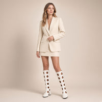 Femme portant les bottes hautes ajourées effet vinyle blanc cassé, en pied sur fond beige