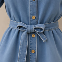 Détail de la ceinture nouée, des boutons dorés et du grain du denim délavé – SAKIWÉ