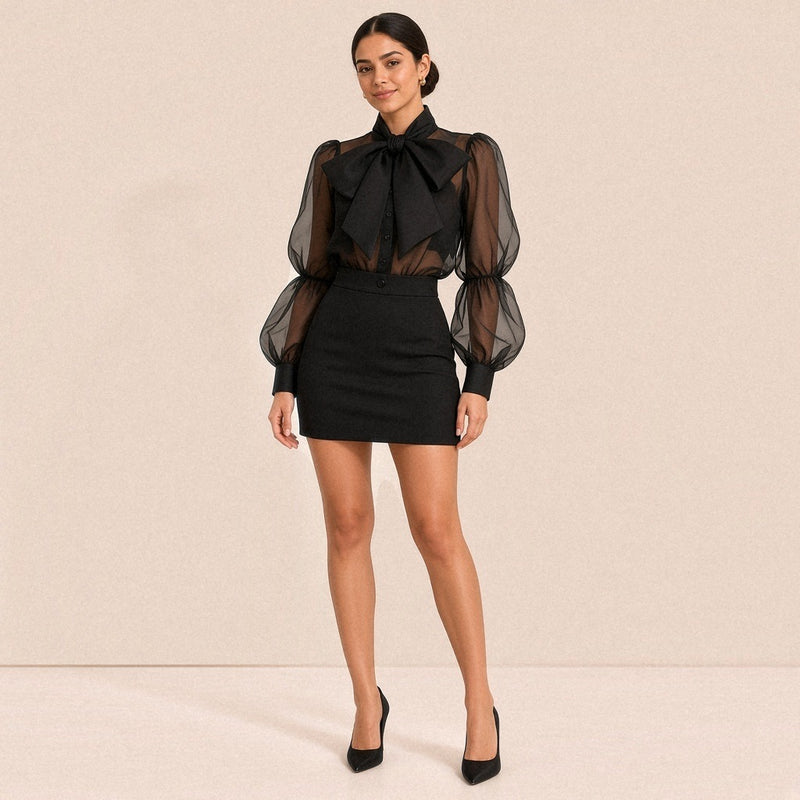 Ensemble noir porté de face : chemise en voile transparent à grand nœud lavallière et jupe crayon mini taille haute