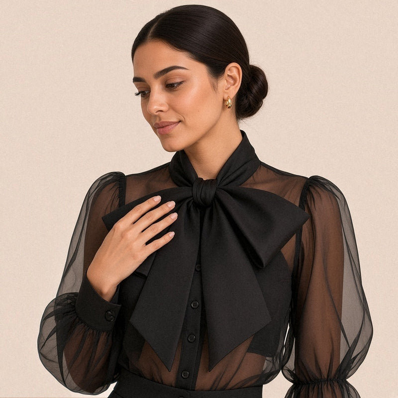 Gros plan sur le col montant et le grand nœud lavallière de la chemise noire en voile transparent