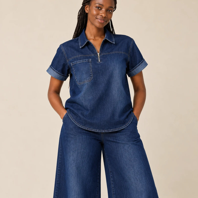 Détail du haut en denim bleu avec col, fermeture courte et poche poitrine
