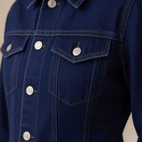 Détail des poches à rabat et des boutons argentés de la veste en jean brut – SAKIWÉ