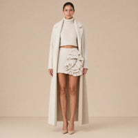 Ensemble trois pièces en maille : manteau long, col roulé et jupe à volants, beige avoine, porté de face en pied