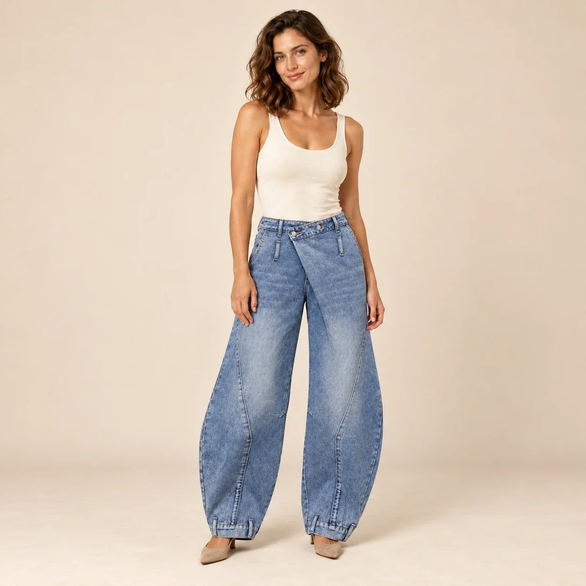 Jean ballon bleu à taille asymétrique porté de face sur fond crème