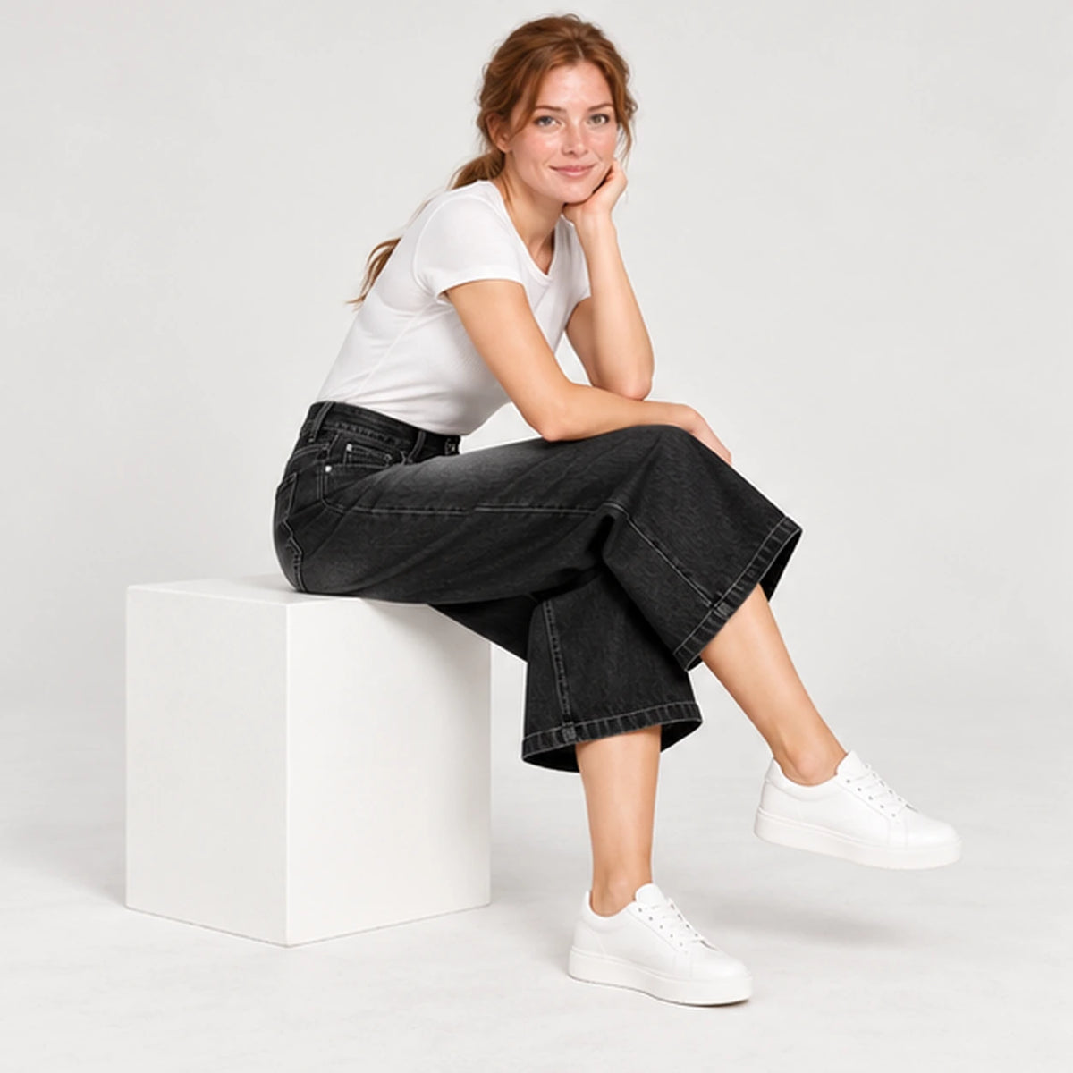 Jean corsaire femme noir, pose assise montrant le volume ample des jambes raccourcies