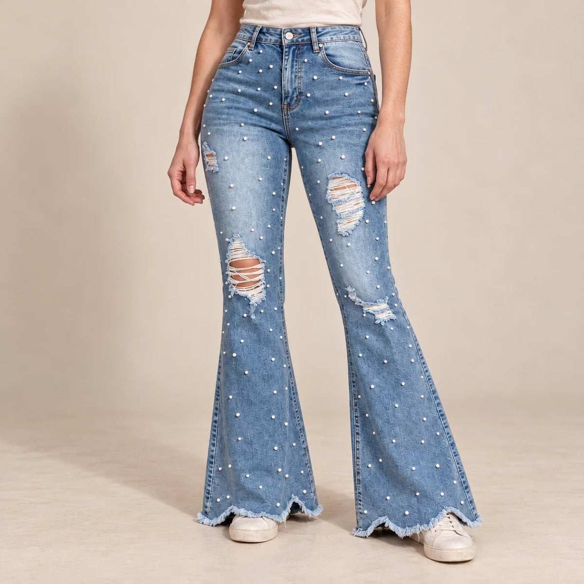 Jean évasé bleu à perles et déchirures, détail des jambes évasées et des ourlets effilochés