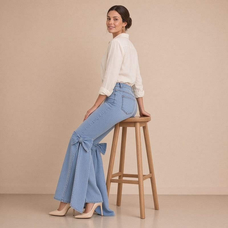 Jean flare bleu clair porté assise sur un tabouret : nœuds en denim visibles à l’arrière des genoux, pans qui tombent jusqu’aux talons
