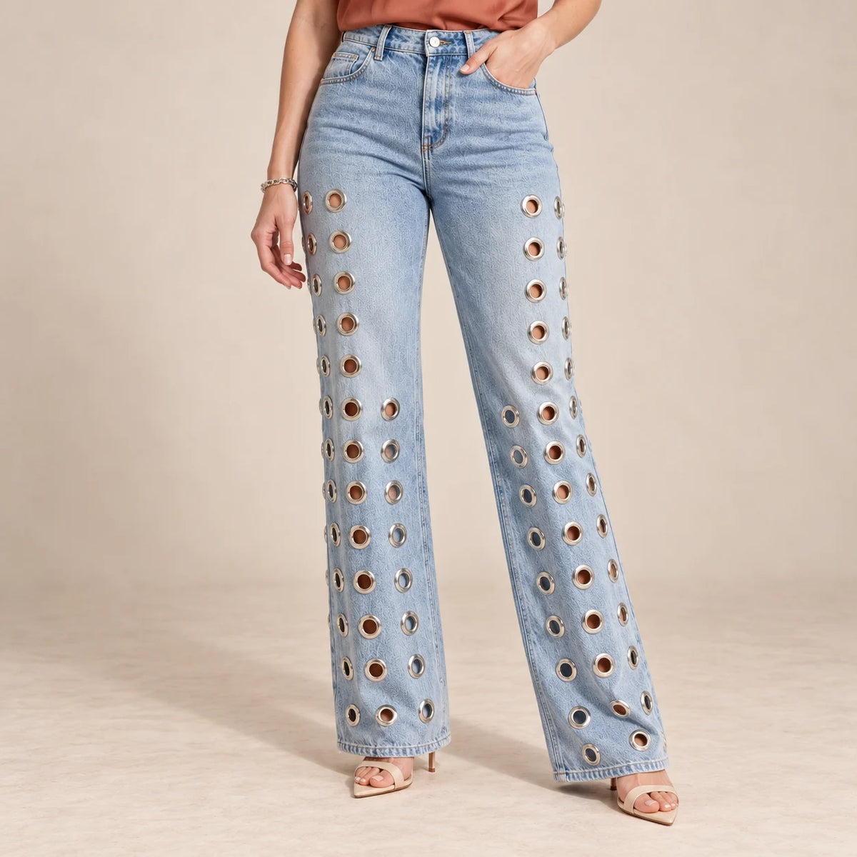 Détail des jambes larges et des œillets métalliques ajourés du jean