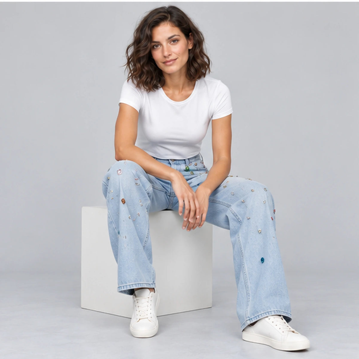 Jean large bleu clair orné de détails multicolores, pose assise