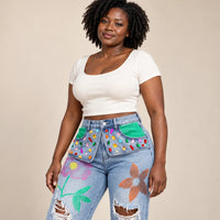 Détail des strass multicolores et des fleurs peintes sur le jean bleu clair