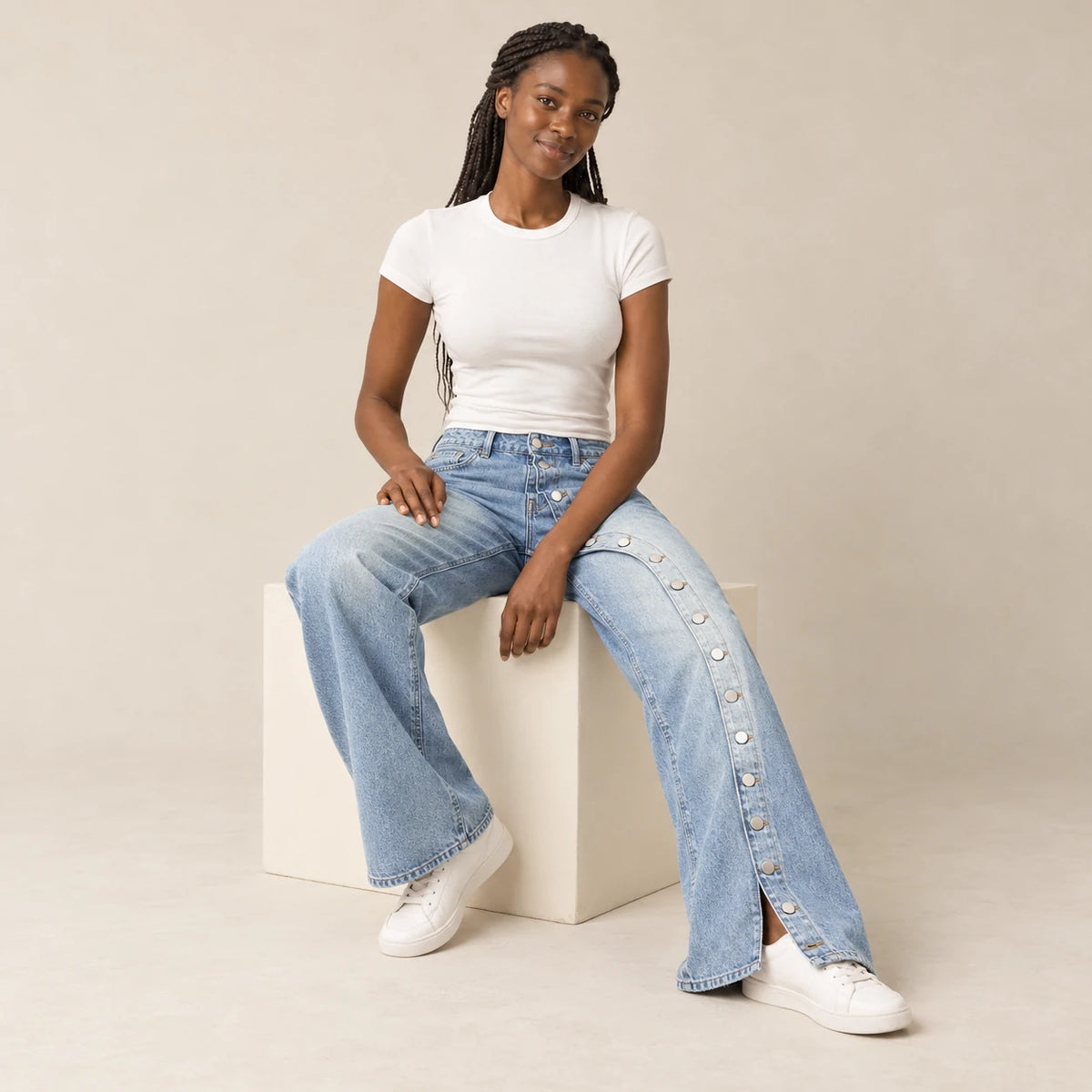Mannequin africaine assise portant le jean large bleu à boutons latéraux