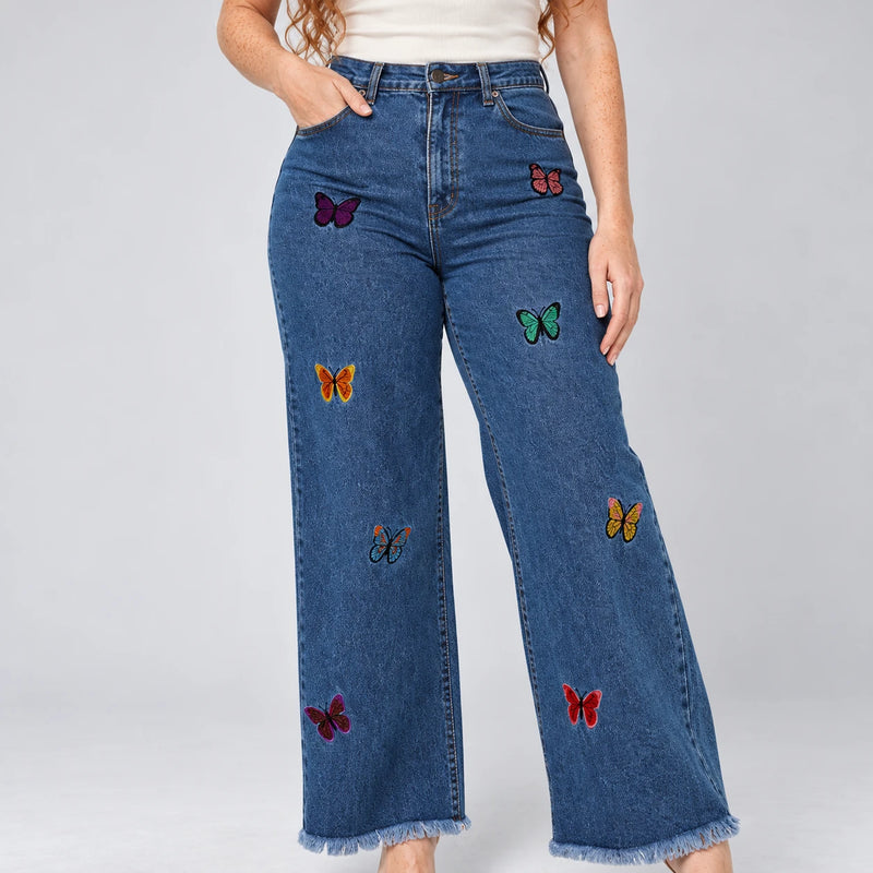 Détail des broderies papillons colorées sur le denim bleu foncé