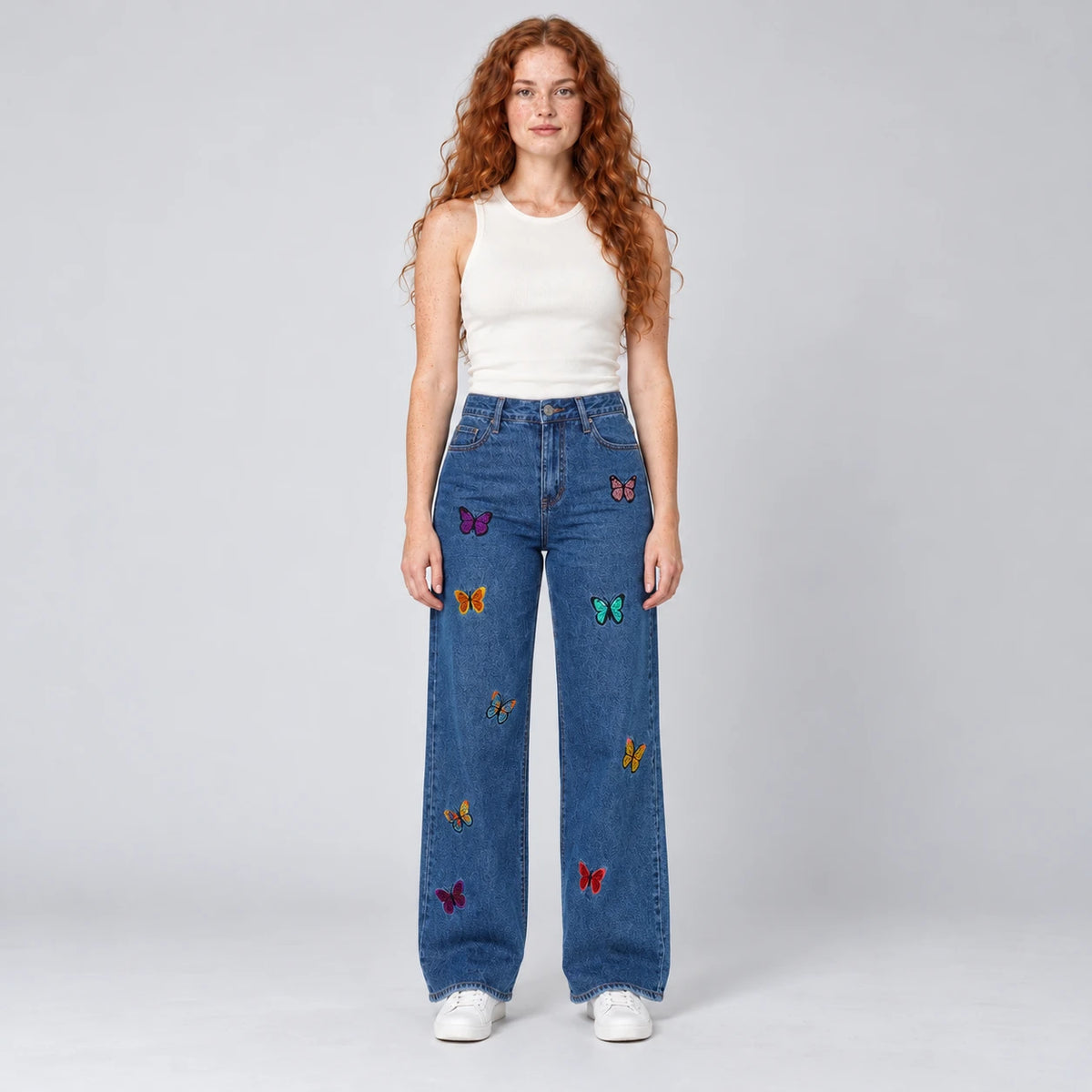Vue de face du jean large bleu à broderies papillons multicolores