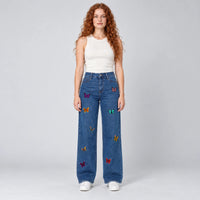 Vue de face du jean large bleu à broderies papillons multicolores