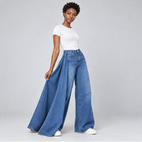 Détail porté du long panneau drapé sur un jean large bleu délavé