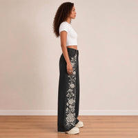 Jean large noir délavé, profil montrant la broderie de roses blanches le long de la jambe droite – SAKIWÉ