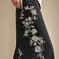 Détail de la broderie de roses blanches sur le jean noir délavé – SAKIWÉ