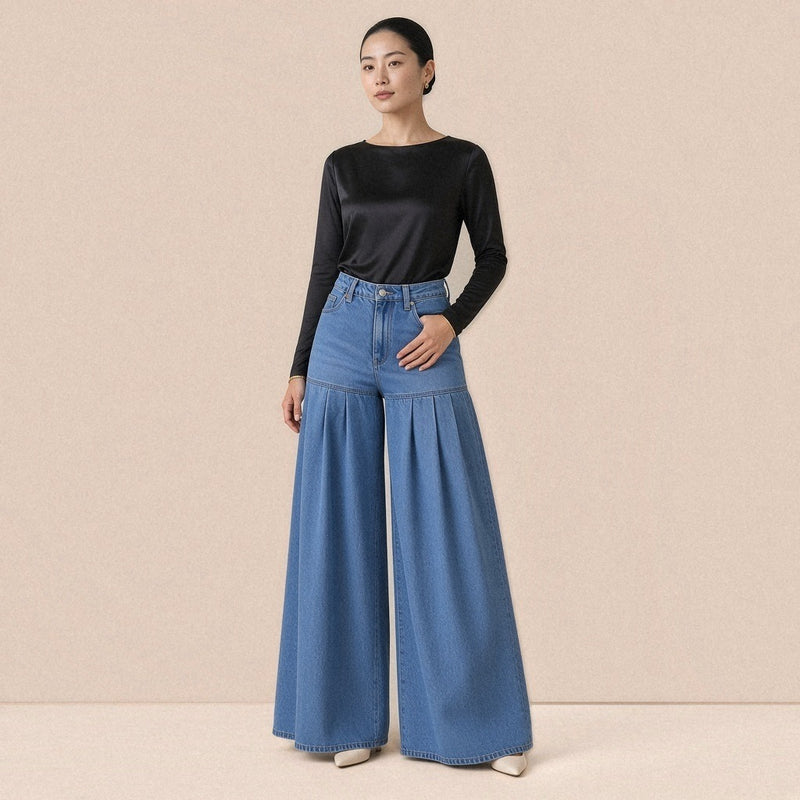 Jean palazzo taille haute SAKIWE bleu délavé porté de face avec un body en satin noir, jambes extra-larges plissées