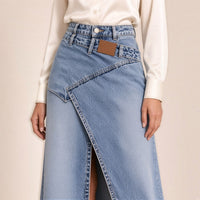 Détail de la taille de la jupe longue en jean bleu clair : ceinture croisée et étiquette