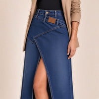 Détail de la taille de la jupe longue en jean bleu foncé : ceinture croisée et fente haute