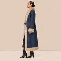 Manteau long en jean SAKIWE bordé de fausse fourrure porté de profil