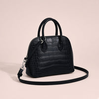 Mini sac bowling en cuir effet croco noir vu de trois quarts, deux anses roulées et double zip argenté