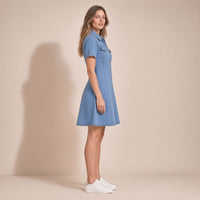 Femme de profil portant la robe chemise en jean bleu clair, silhouette évasée