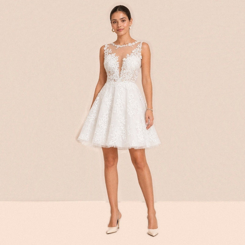 Robe courte en dentelle blanche portée de face, encolure illusion et jupe en tulle évasée