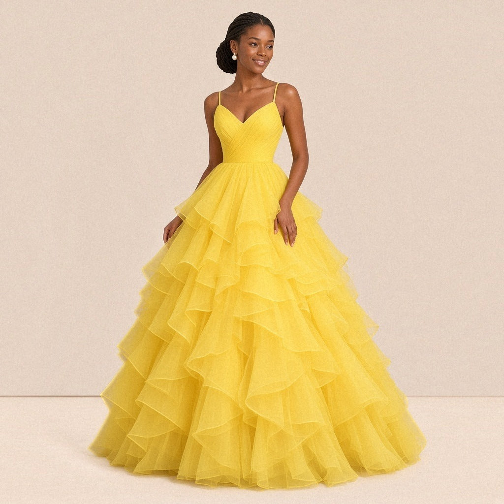 Robe de bal longue jaune en tulle à volants, portée de face, bretelles fines et buste drapé en V