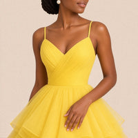 Gros plan sur le buste drapé en V et les volants de tulle de la robe de bal jaune