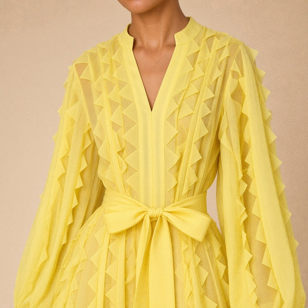 Robe fluide en voile SAKIWE jaune portée, en gros plan sur le col V, les volants et la ceinture