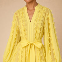 Robe fluide en voile SAKIWE jaune portée, en gros plan sur le col V, les volants et la ceinture