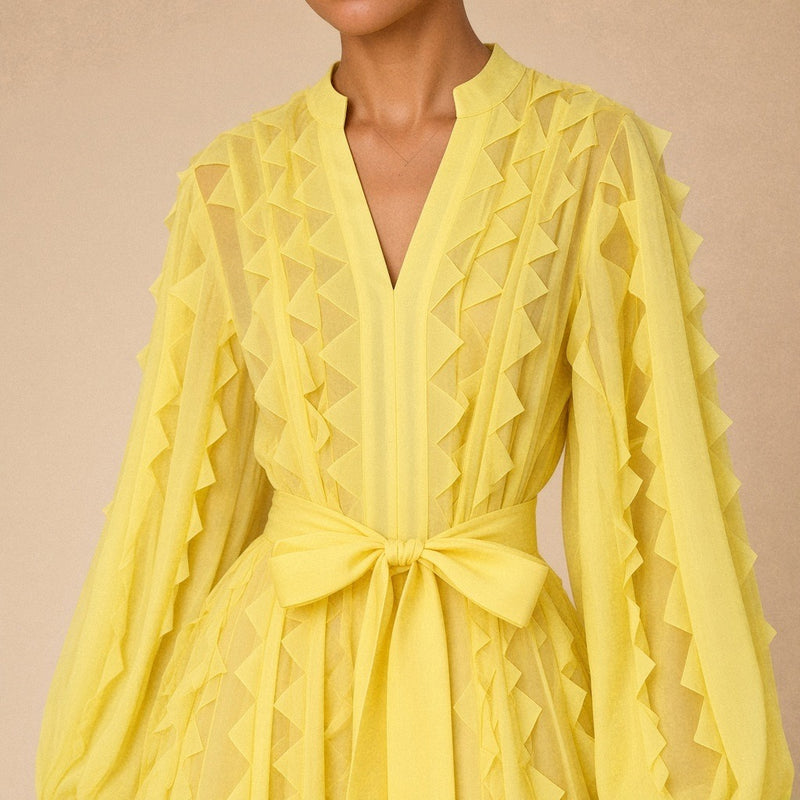 Robe fluide en voile SAKIWE jaune portée, en gros plan sur le col V, les volants et la ceinture