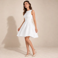 Robe de mariée courte blanche à taille marquée et plis, vue de trois quarts