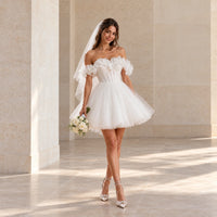 Robe de mariée courte blanche à épaules dénudées et volants, portée de face