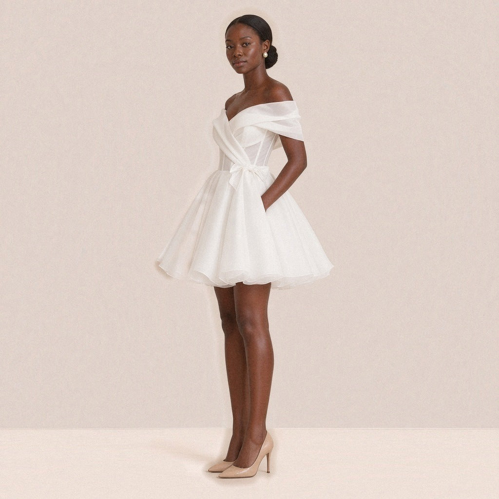 Femme de trois quarts dans la robe de mariée courte, petit nœud sur la hanche