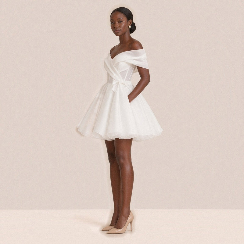 Femme de trois quarts dans la robe de mariée courte, petit nœud sur la hanche