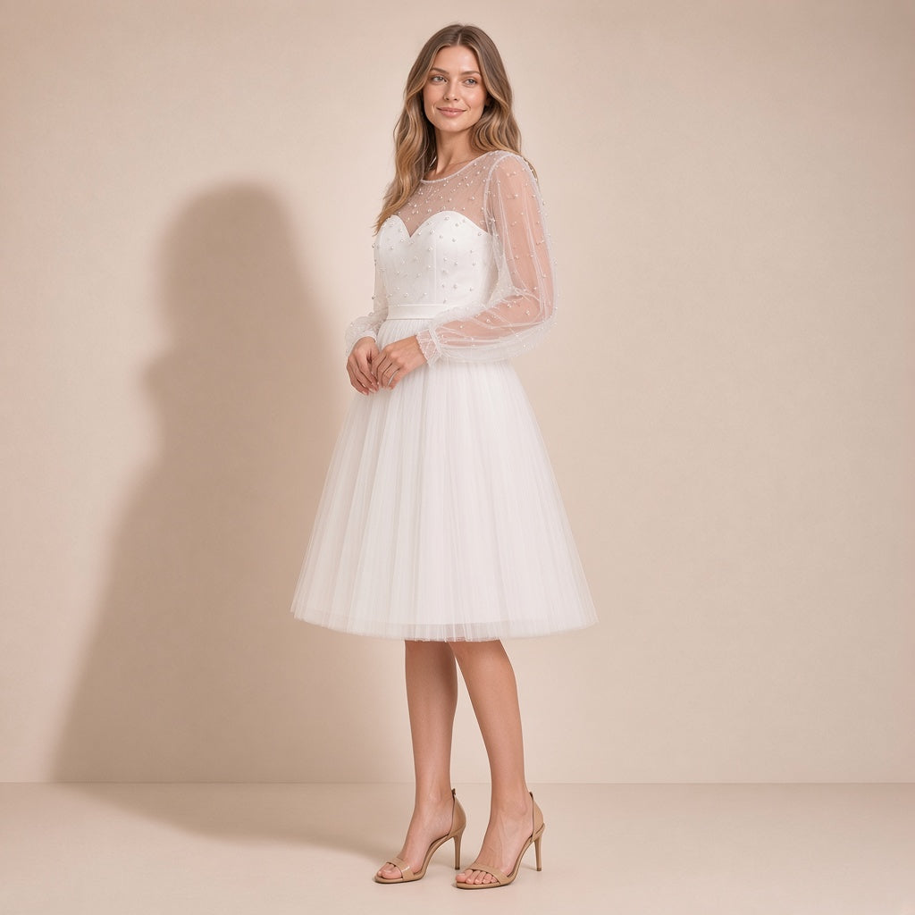 Femme de trois quarts dans la robe de mariée courte ivoire en tulle, main à la taille