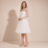 Femme de trois quarts dans la robe de mariée courte ivoire en tulle, main à la taille