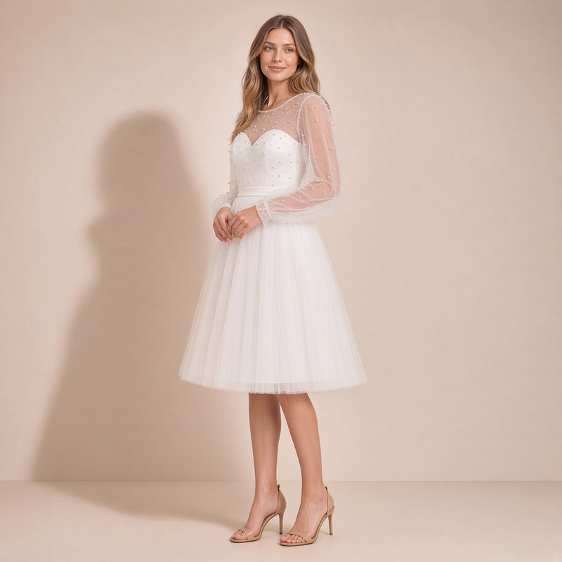 Femme de trois quarts dans la robe de mariée courte ivoire en tulle, main à la taille