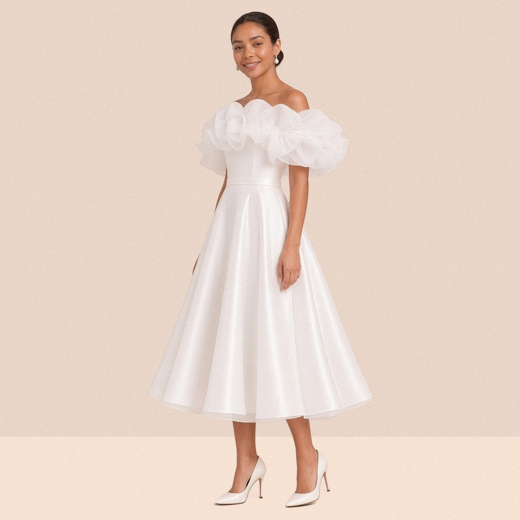 Robe de mariée blanche courte à épaules dénudées et volants en organza – vue de trois quarts.