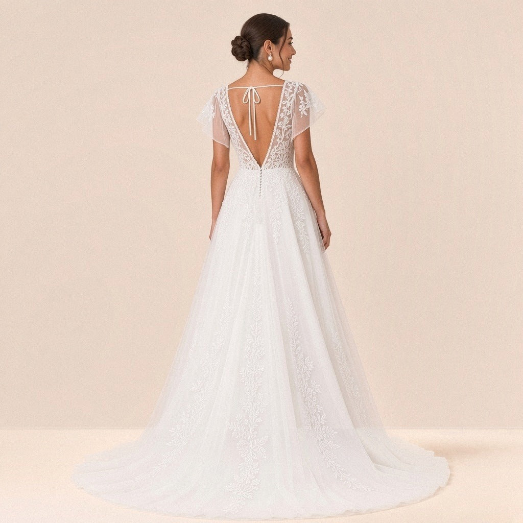 Robe de mariée en dentelle vue de dos : dos ouvert en V, cordon noué et petite traîne en tulle